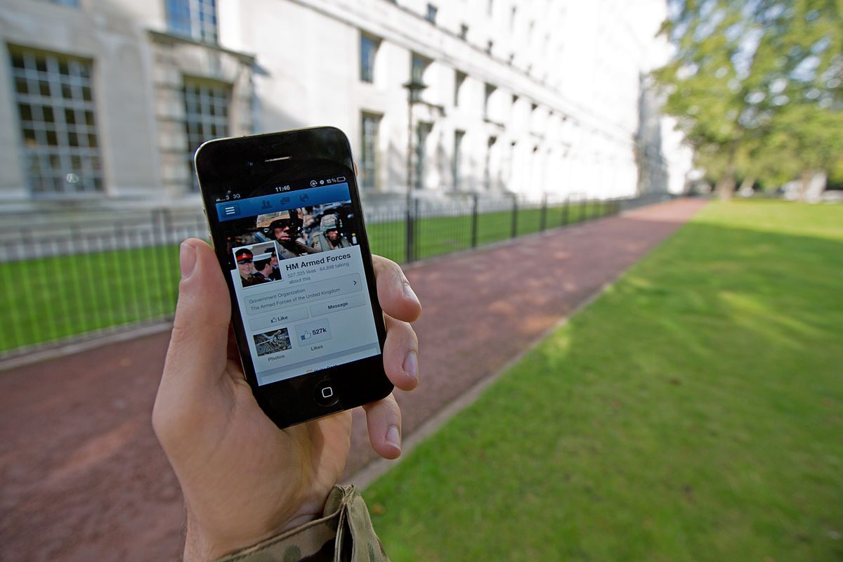 Serviceman accessing social media on smartphone outside military building