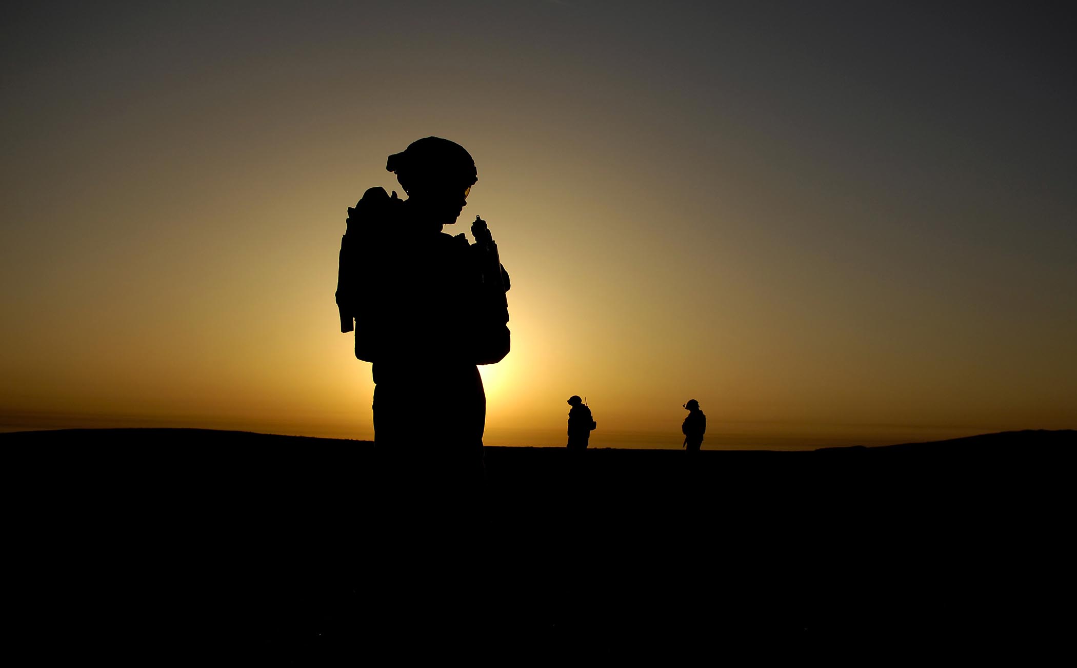 A U.S. Army soldier stands in silhouette at sunset in Iraq, in a reflective moment